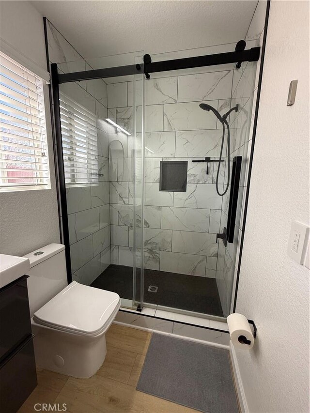 bathroom with toilet, vanity, hardwood / wood-style floors, a textured ceiling, and an enclosed shower