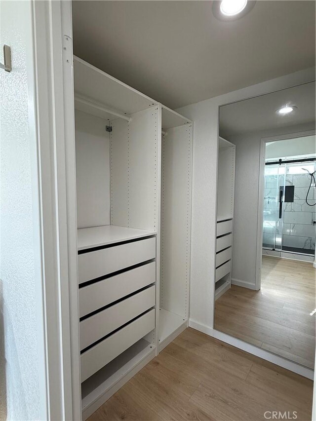 walk in closet with light hardwood / wood-style flooring