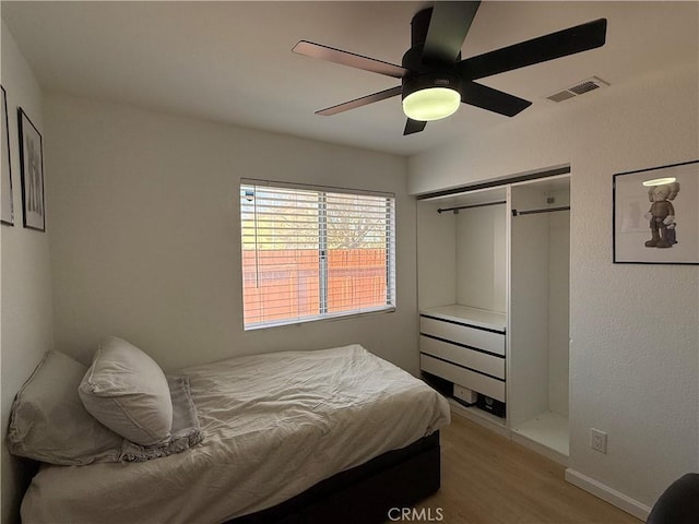 bedroom featuring light wood-type flooring, ceiling fan, and a closet