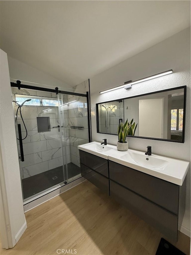 bathroom featuring lofted ceiling, walk in shower, hardwood / wood-style flooring, and vanity