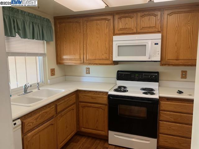 kitchen featuring dark wood-type flooring, sink, and white appliances