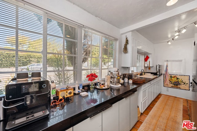 kitchen featuring light tile patterned floors, white cabinetry, and sink