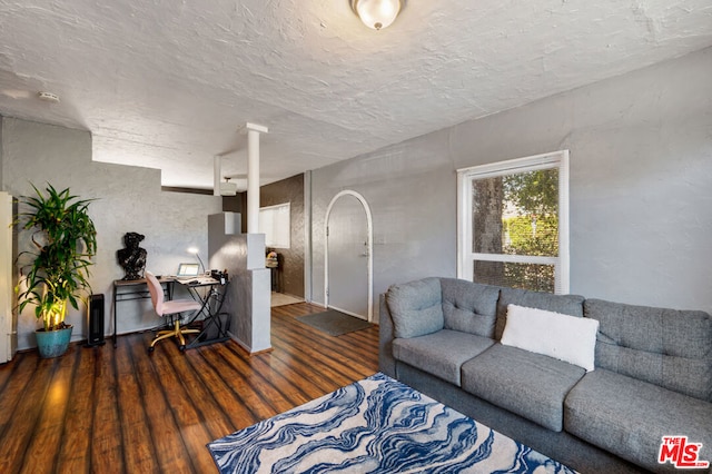 living room featuring dark wood-type flooring and a textured ceiling