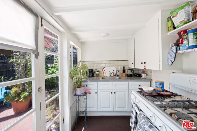 kitchen with decorative backsplash, sink, white cabinetry, and gas range gas stove