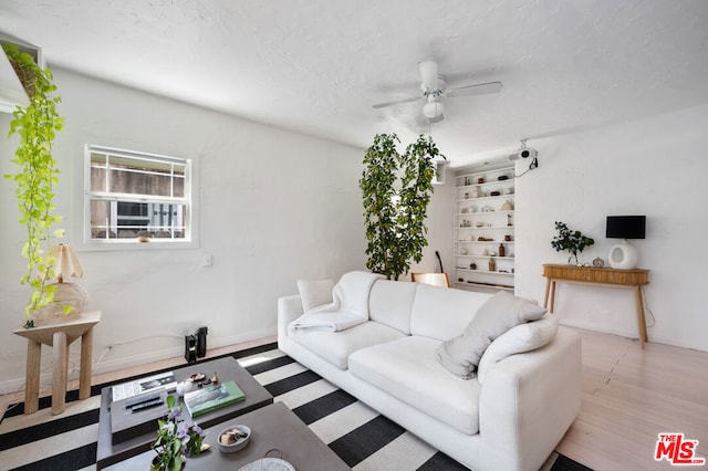 living room with ceiling fan, a textured ceiling, and light wood-type flooring