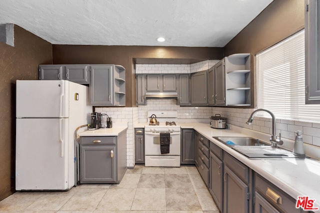 kitchen with gray cabinetry, backsplash, sink, and white appliances