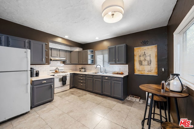 kitchen featuring decorative backsplash, sink, white appliances, and gray cabinets