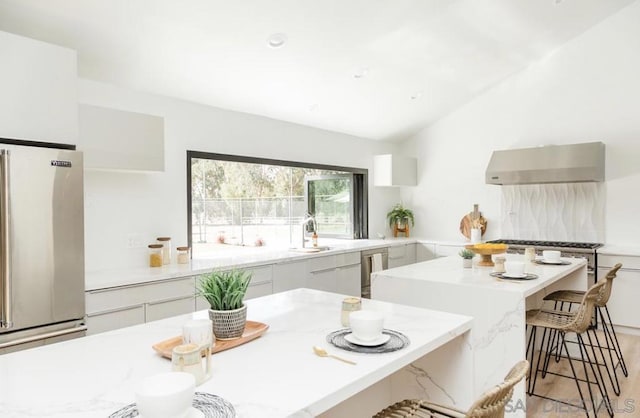 kitchen with a kitchen island, sink, white cabinetry, a breakfast bar area, and stainless steel appliances