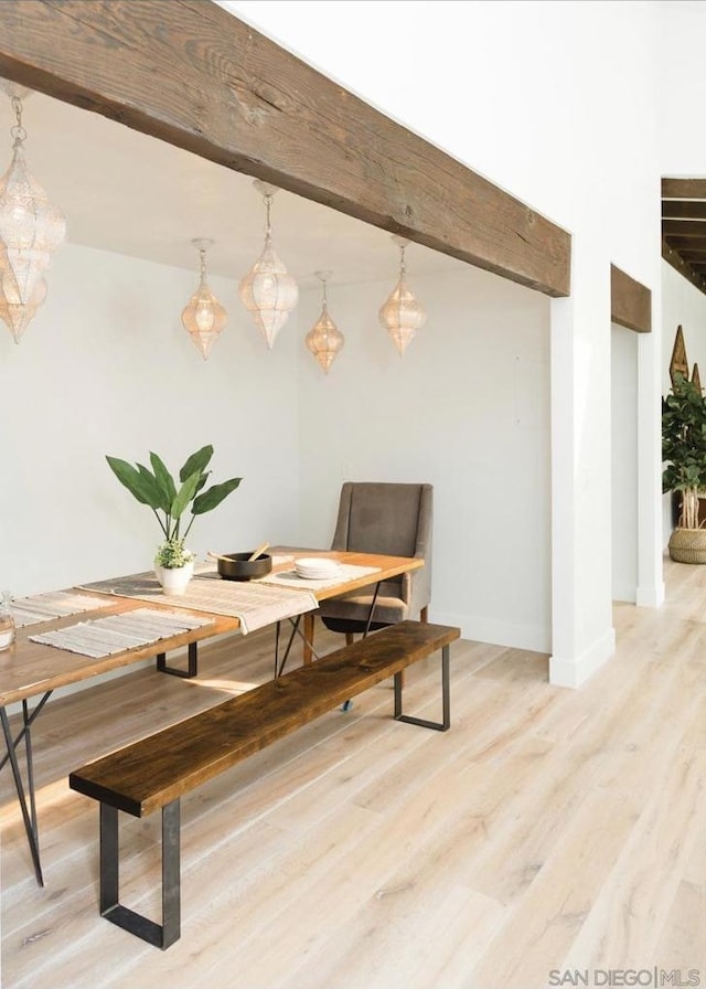 dining room featuring light wood-type flooring and beamed ceiling