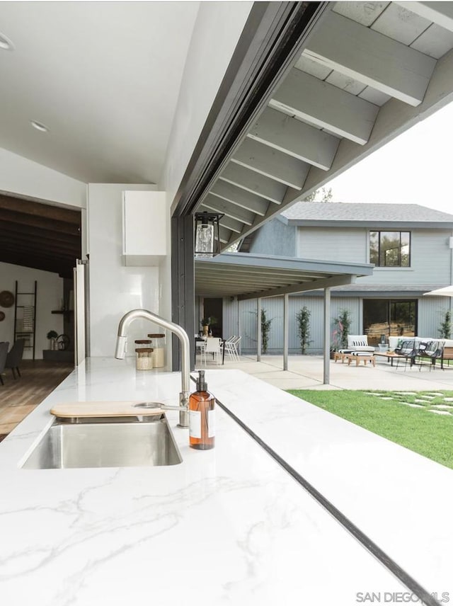 kitchen featuring sink, white cabinetry, and lofted ceiling with beams