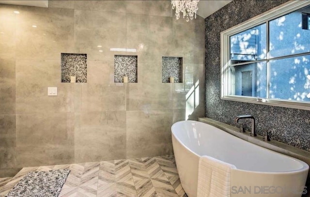 bathroom with a tub and a notable chandelier