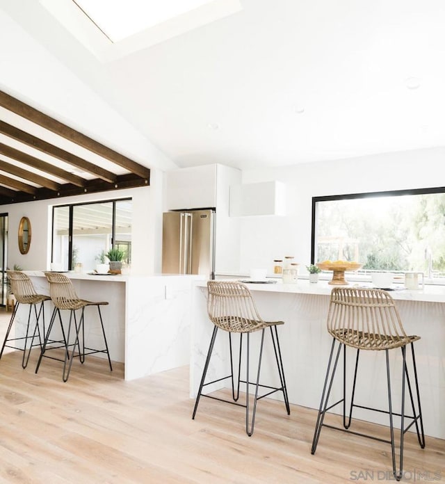 kitchen with a breakfast bar area, white cabinetry, kitchen peninsula, and high end fridge