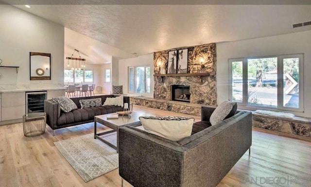 living room featuring lofted ceiling, a wealth of natural light, a fireplace, and beverage cooler