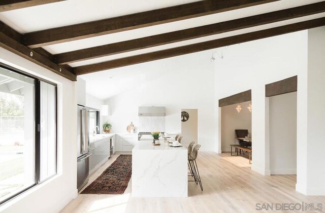 interior space with light hardwood / wood-style floors, vaulted ceiling with beams, and sink