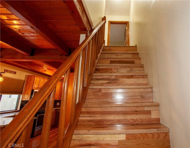 stairway featuring wood ceiling, beam ceiling, and wood-type flooring