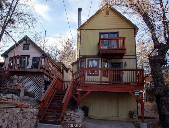 rear view of property featuring a wooden deck and a balcony