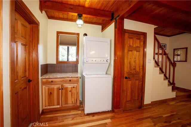 laundry area with a barn door, stacked washer and dryer, wood ceiling, and light hardwood / wood-style floors