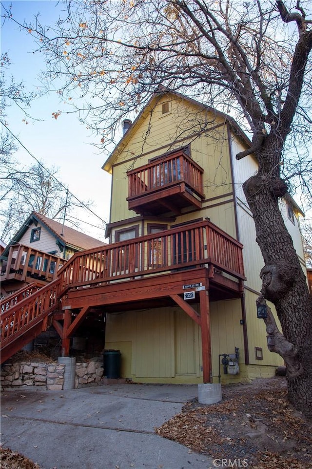 back of property featuring a balcony and a wooden deck