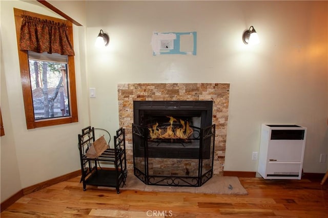 living area featuring heating unit, a fireplace, and hardwood / wood-style flooring