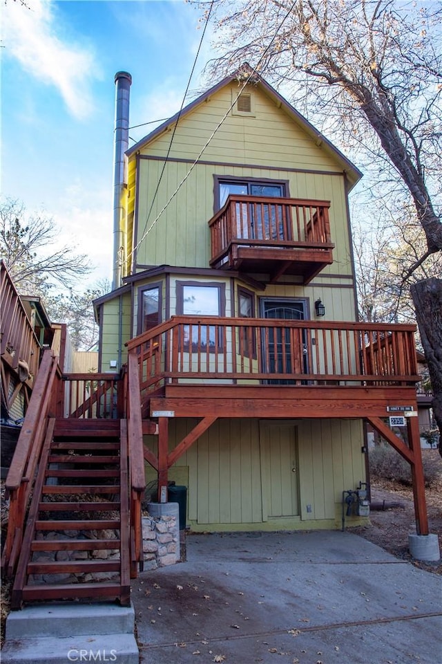 rear view of property featuring a balcony and a wooden deck