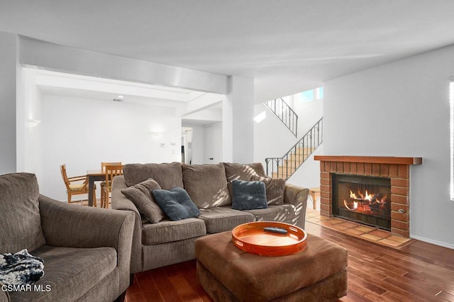 living room featuring dark wood-type flooring and a brick fireplace