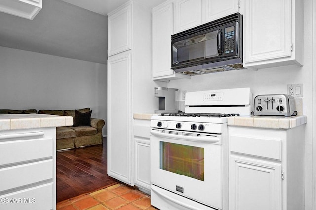 kitchen with white cabinets, light tile patterned floors, and white gas range oven