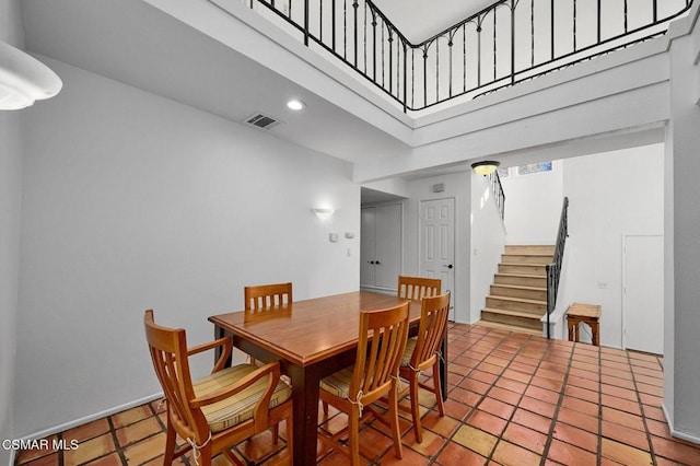 tiled dining space featuring a towering ceiling