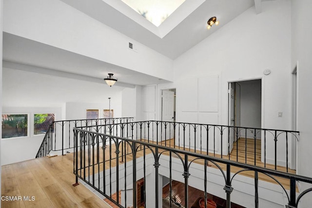 hallway with high vaulted ceiling, beam ceiling, and light wood-type flooring