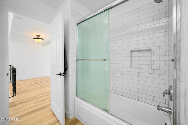 bathroom with hardwood / wood-style flooring and bath / shower combo with glass door