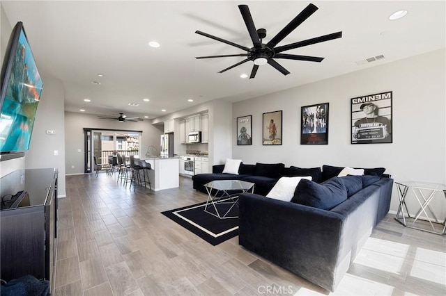 living room with ceiling fan and light hardwood / wood-style flooring