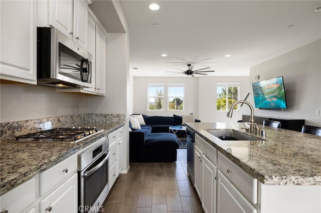 kitchen with sink, white cabinetry, appliances with stainless steel finishes, and a kitchen island with sink