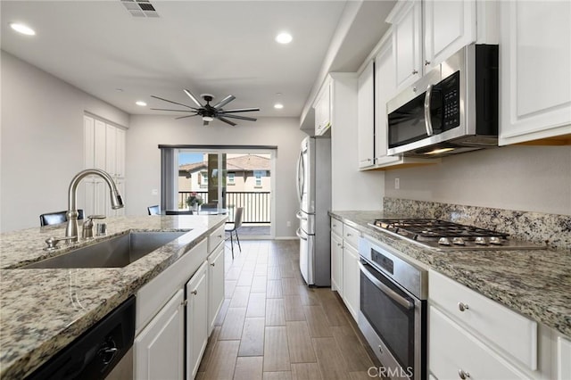 kitchen featuring light stone counters, sink, white cabinetry, and stainless steel appliances