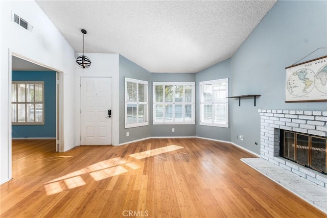 unfurnished living room with a fireplace, a wealth of natural light, hardwood / wood-style flooring, and vaulted ceiling