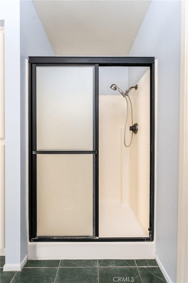 bathroom with tile patterned flooring, lofted ceiling, and a shower with shower door