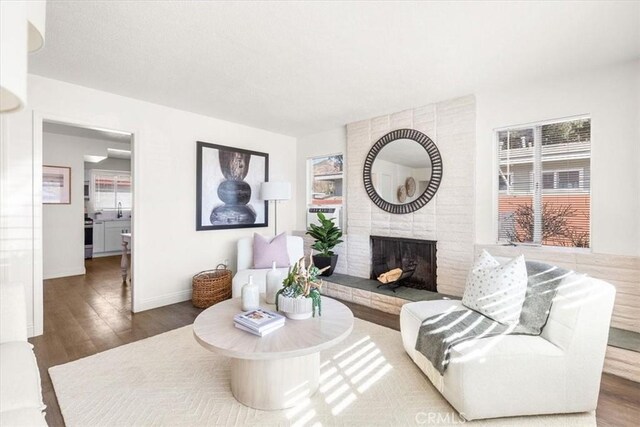 living room featuring a brick fireplace and dark hardwood / wood-style floors