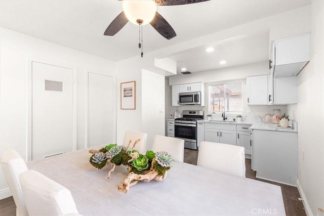 dining room with ceiling fan, sink, and dark wood-type flooring