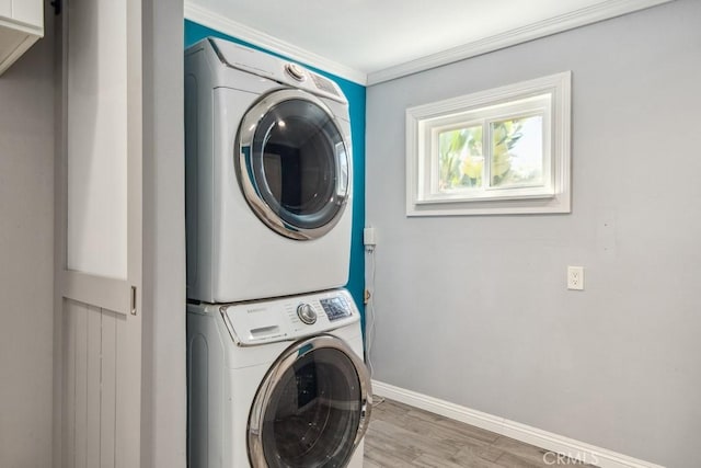 laundry room featuring hardwood / wood-style flooring, ornamental molding, and stacked washer and dryer