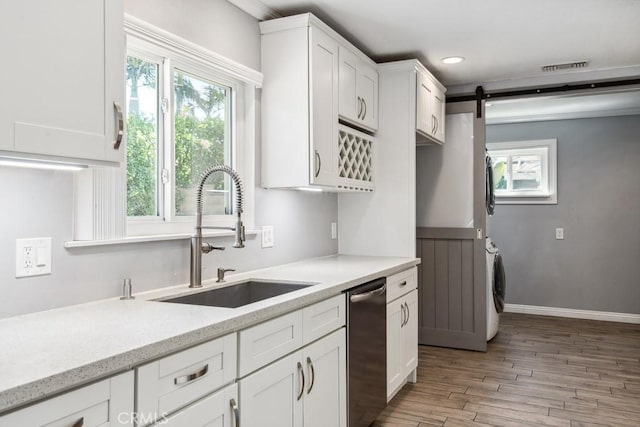 kitchen with sink, white cabinetry, dishwasher, and a barn door