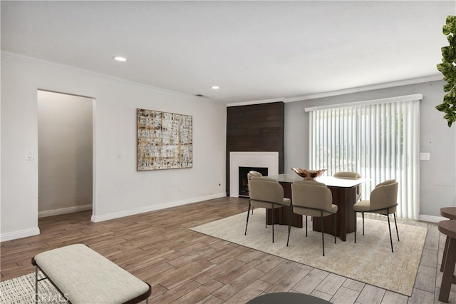 dining room featuring a large fireplace, crown molding, and light hardwood / wood-style floors