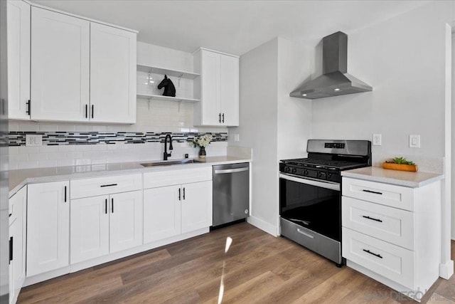 kitchen with hardwood / wood-style floors, appliances with stainless steel finishes, sink, white cabinets, and wall chimney exhaust hood