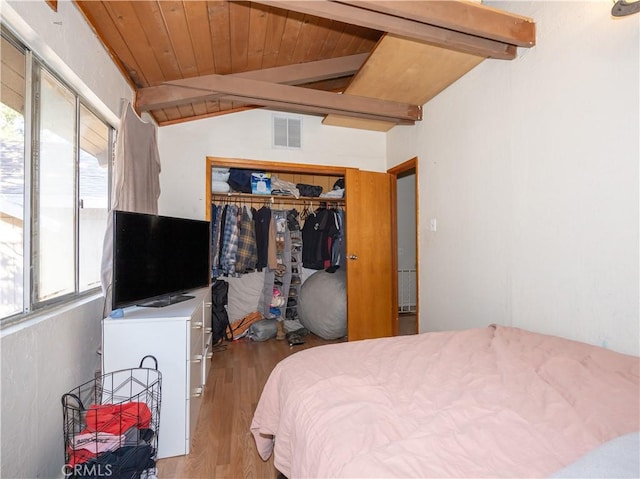 bedroom featuring vaulted ceiling with beams, light wood-type flooring, multiple windows, and a closet