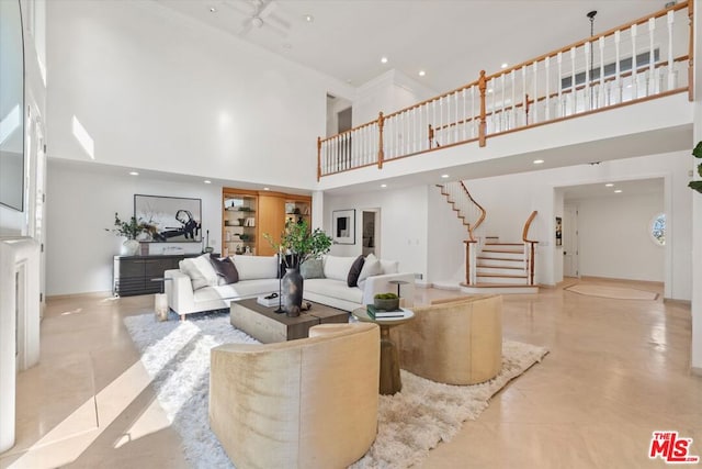 living room featuring ceiling fan, built in shelves, and a towering ceiling