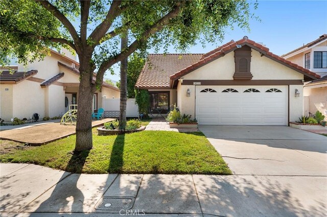 mediterranean / spanish house with a garage and a front lawn