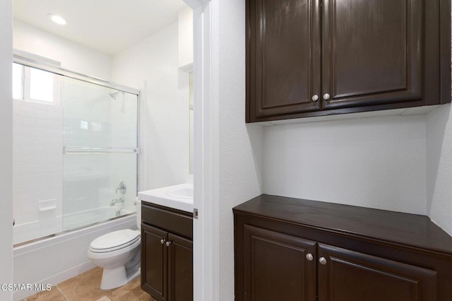 full bathroom with bath / shower combo with glass door, toilet, vanity, and tile patterned flooring