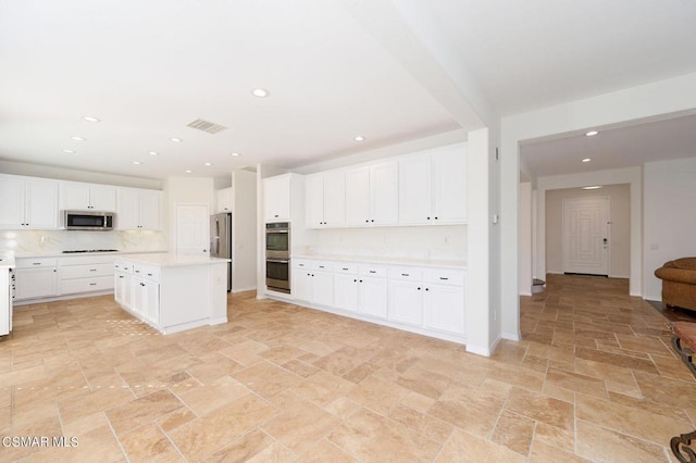 kitchen featuring stainless steel appliances, white cabinetry, and a center island