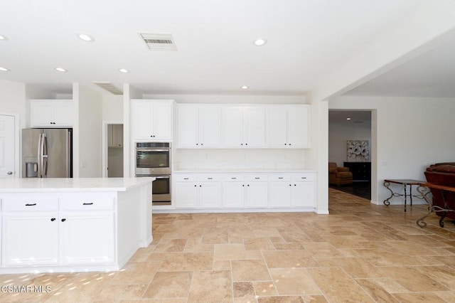 kitchen with appliances with stainless steel finishes, white cabinets, and a kitchen island