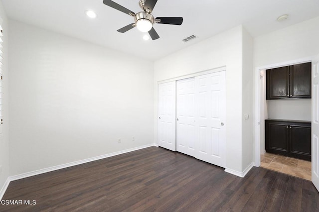 unfurnished bedroom with ceiling fan, dark hardwood / wood-style flooring, and a closet