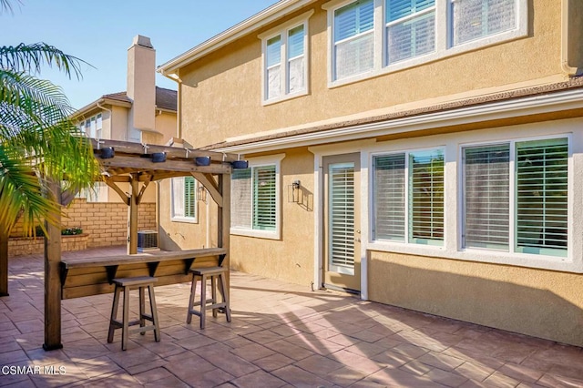 back of house with central air condition unit, a pergola, and a patio