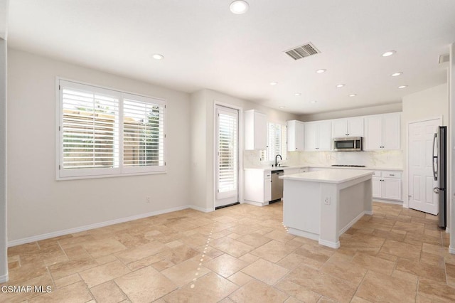 kitchen featuring backsplash, a kitchen island, sink, white cabinetry, and appliances with stainless steel finishes