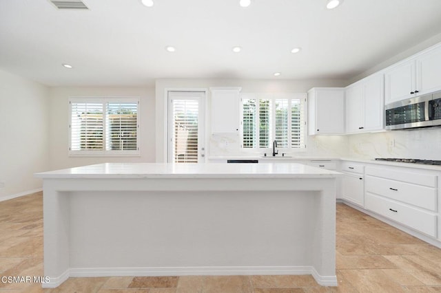 kitchen with white cabinetry, sink, gas stovetop, and a center island